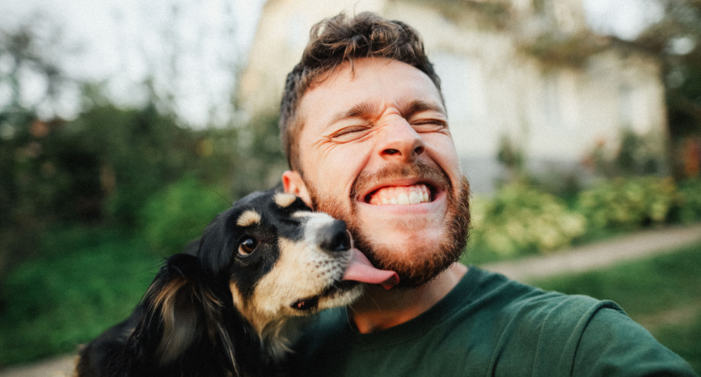 Man wordt in zijn gezicht gelikt door hond.